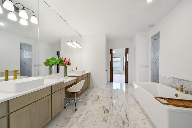 full bath with a soaking tub, marble finish floor, two vanities, and a sink