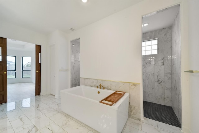 full bath featuring a freestanding bath, marble finish floor, a wainscoted wall, and a marble finish shower