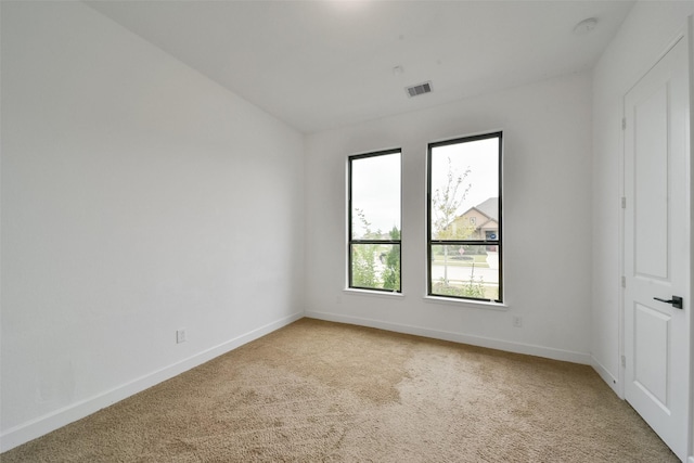 spare room with baseboards, visible vents, and light colored carpet