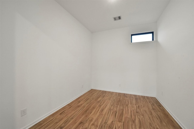 unfurnished room featuring wood finished floors, visible vents, and baseboards