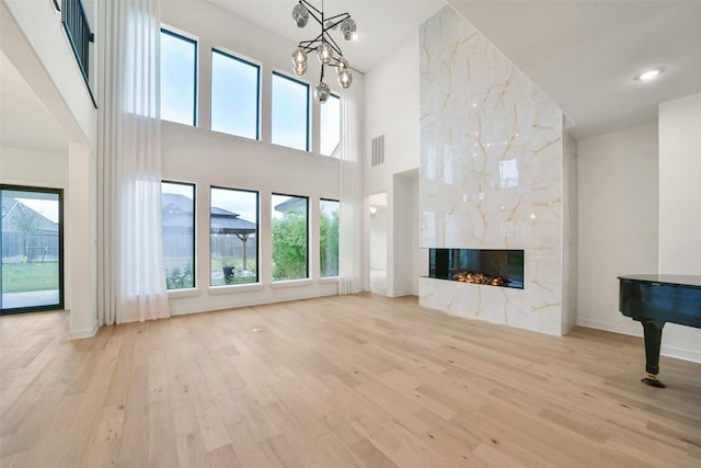 unfurnished living room featuring baseboards, visible vents, a premium fireplace, wood finished floors, and recessed lighting