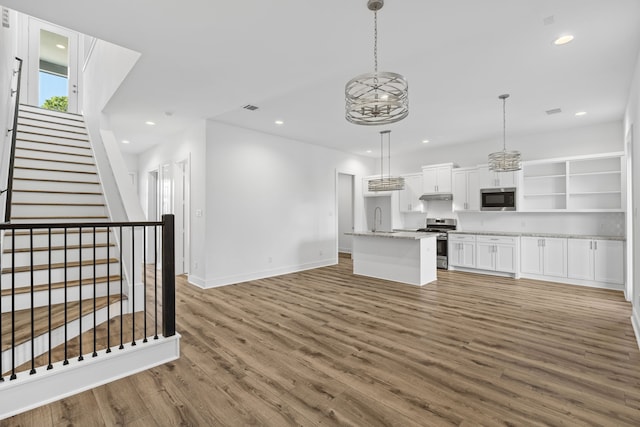 interior space featuring a sink, wood finished floors, open shelves, white cabinetry, and appliances with stainless steel finishes