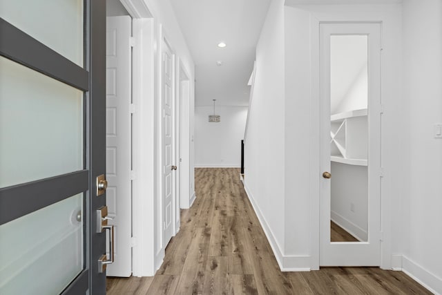 corridor with wood finished floors, baseboards, and recessed lighting