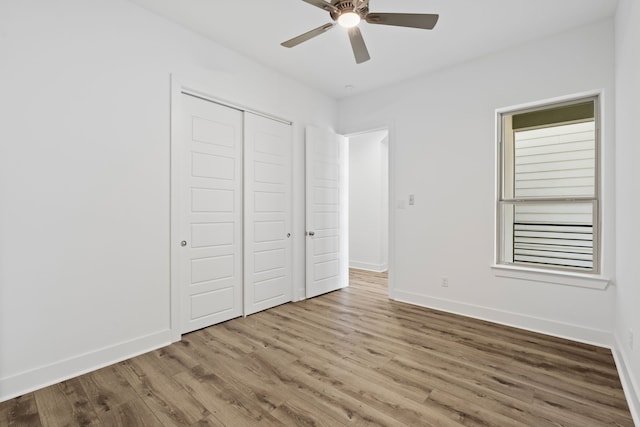 unfurnished bedroom with a closet, baseboards, a ceiling fan, and wood finished floors
