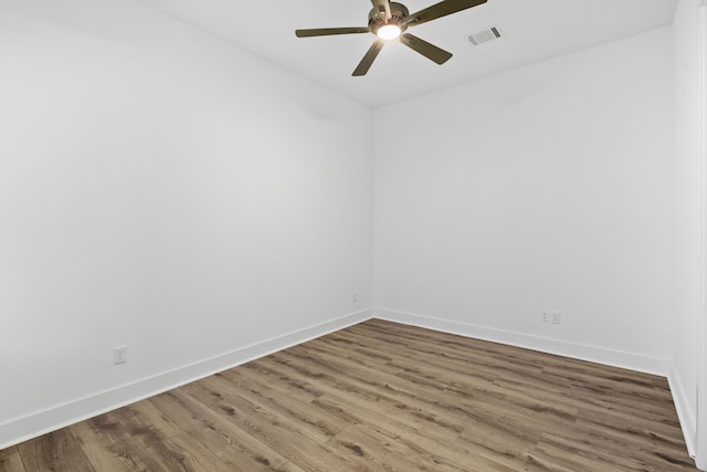 unfurnished room featuring baseboards, visible vents, a ceiling fan, and wood finished floors