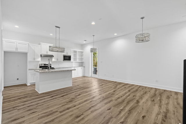 kitchen with stainless steel microwave, recessed lighting, light wood-style floors, and white cabinets