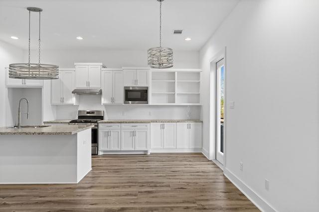 kitchen featuring a sink, open shelves, visible vents, under cabinet range hood, and appliances with stainless steel finishes