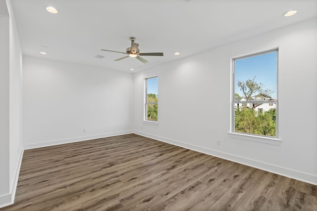 empty room with a wealth of natural light, wood finished floors, baseboards, and recessed lighting