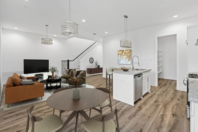 interior space featuring dishwasher, white cabinetry, light wood-style flooring, and a sink
