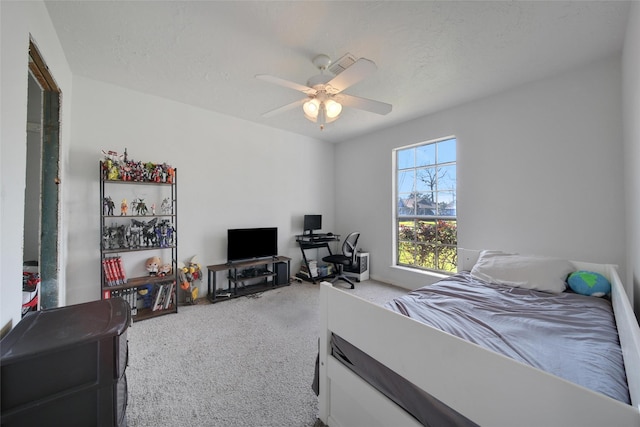 carpeted bedroom featuring a ceiling fan and a textured ceiling