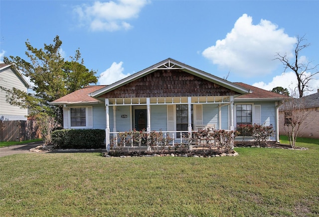 view of front of home with covered porch, fence, and a front lawn