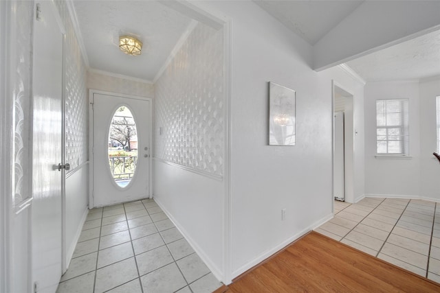 entryway with a wealth of natural light, crown molding, and light tile patterned flooring