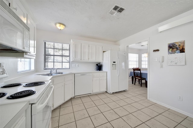 kitchen with light tile patterned floors, visible vents, white cabinetry, a sink, and white appliances