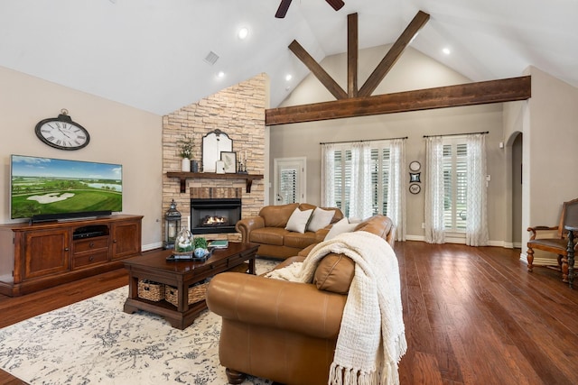 living room with arched walkways, a fireplace, visible vents, wood finished floors, and baseboards