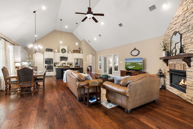 living room featuring a stone fireplace, dark wood finished floors, and visible vents