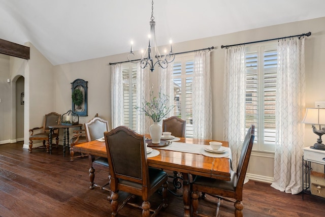 dining space featuring arched walkways, vaulted ceiling, baseboards, and wood finished floors