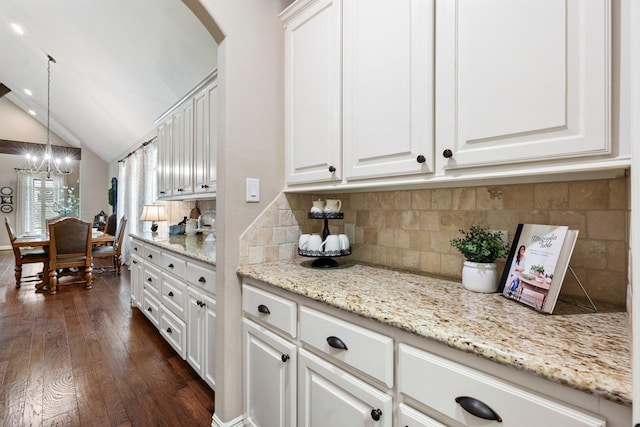 kitchen with arched walkways, dark wood finished floors, lofted ceiling, backsplash, and white cabinets