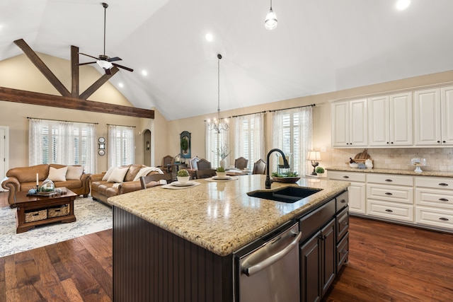 kitchen featuring a sink, arched walkways, open floor plan, and stainless steel dishwasher