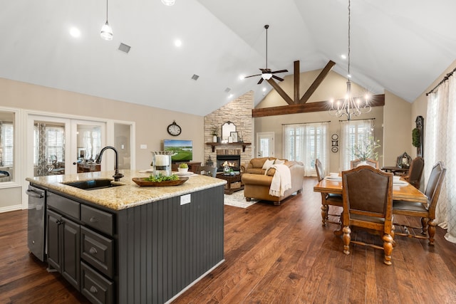 kitchen featuring high vaulted ceiling, a kitchen island with sink, a fireplace, a sink, and dark wood-style floors