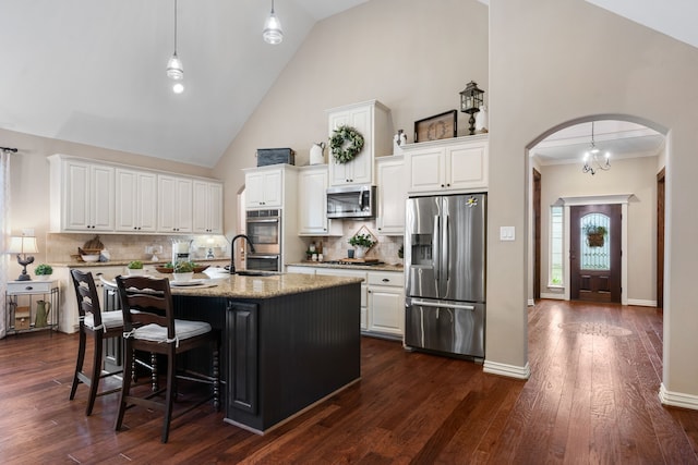 kitchen with white cabinets, arched walkways, and stainless steel appliances