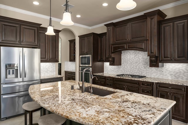 18419 Harlow Dr, Tomball, TX 77377 - kitchen featuring appliances with stainless steel finishes, a sink, arched walkways, dark brown cabinetry, and light stone counters