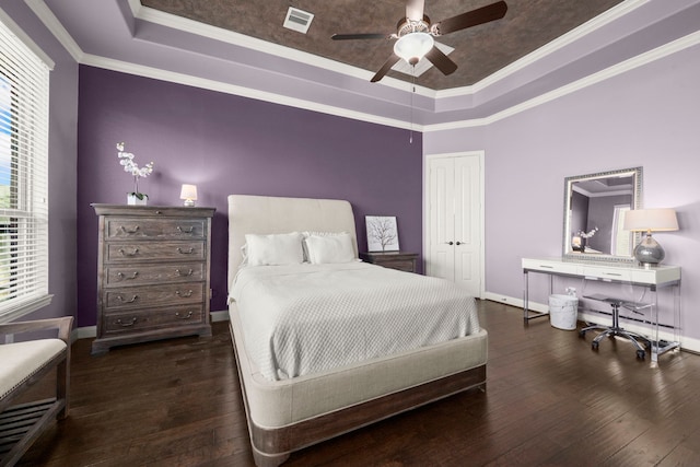 bedroom with a tray ceiling, hardwood / wood-style flooring, visible vents, and baseboards