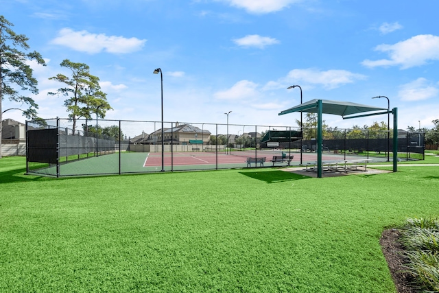 view of tennis court with fence and a lawn