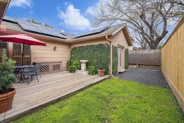 wooden terrace with a fenced backyard, a lawn, and outdoor dining space