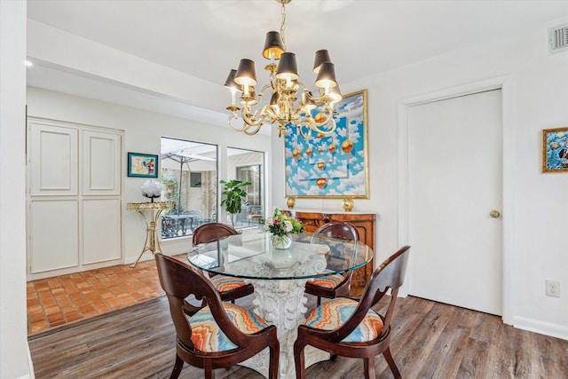 dining area featuring wood finished floors, visible vents, and an inviting chandelier