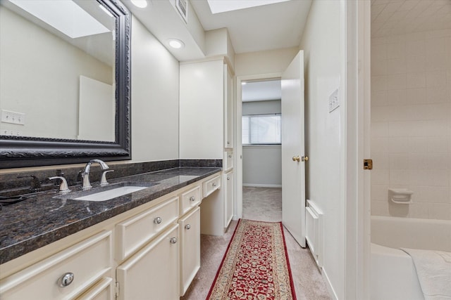 full bathroom featuring a skylight, baseboards, visible vents, and vanity