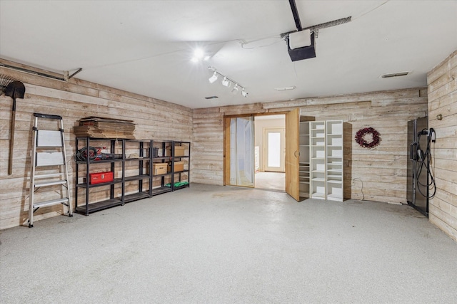 garage with wooden walls, visible vents, and a garage door opener