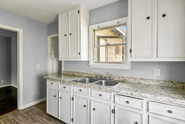 kitchen with baseboards, white cabinetry, dark wood finished floors, and a sink