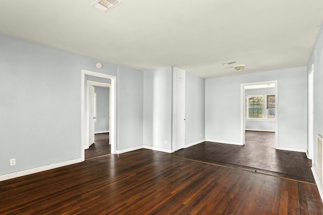 unfurnished room with baseboards, visible vents, and hardwood / wood-style floors