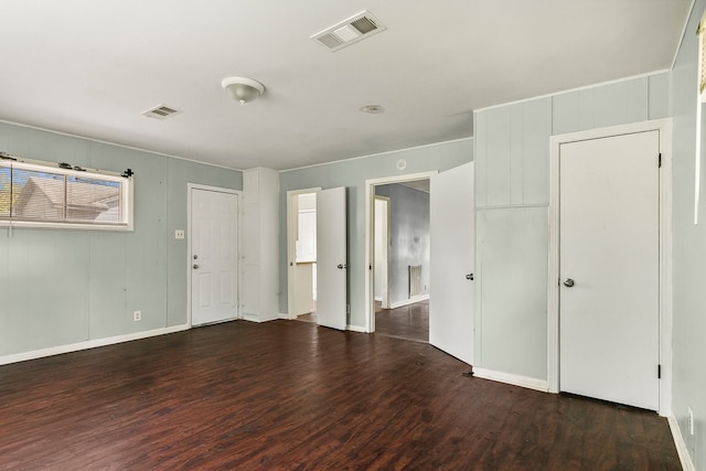 empty room with wood finished floors, visible vents, and baseboards