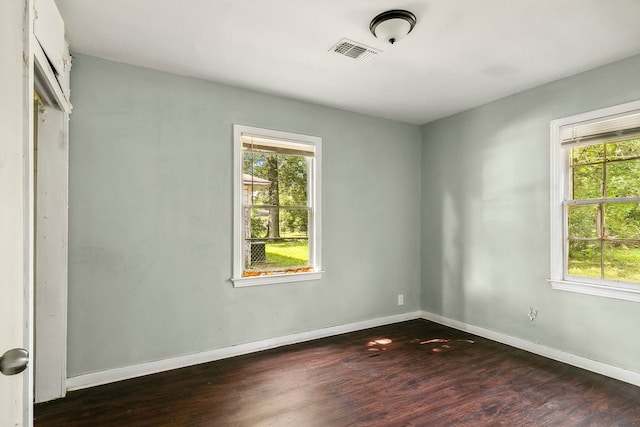 unfurnished room featuring baseboards, visible vents, and dark wood-type flooring