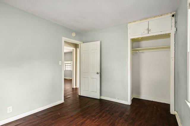 unfurnished bedroom featuring dark wood-style floors, a closet, and baseboards