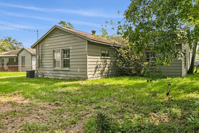 view of side of property featuring central AC unit, a lawn, and fence