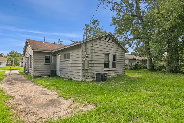 back of house featuring central air condition unit and a yard