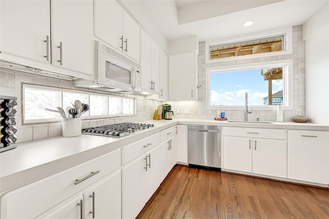 kitchen with stainless steel appliances, light countertops, a sink, and backsplash