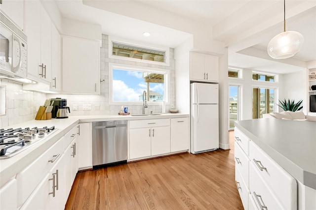 kitchen featuring stainless steel appliances, light wood-style floors, a sink, and decorative backsplash