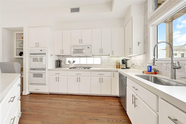 kitchen featuring a sink, visible vents, appliances with stainless steel finishes, backsplash, and light wood finished floors