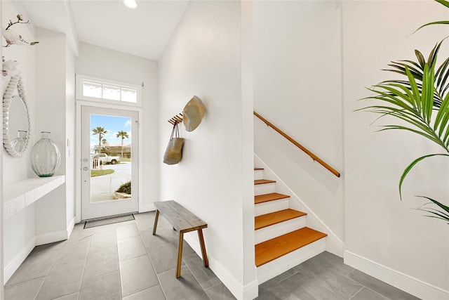 foyer entrance featuring stairway, baseboards, and light tile patterned floors