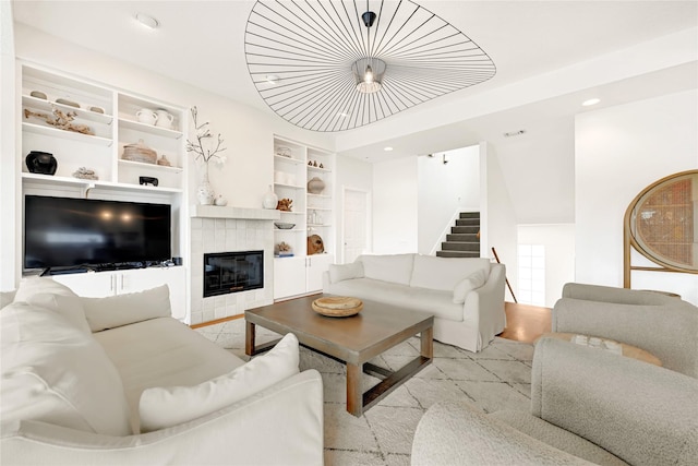 living area featuring stairs, built in shelves, a tiled fireplace, and recessed lighting