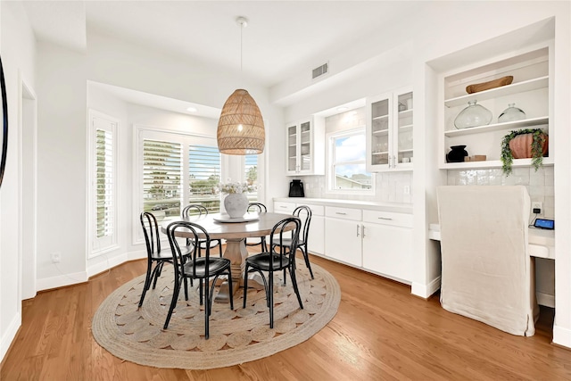 dining space featuring light wood-style flooring, visible vents, and baseboards