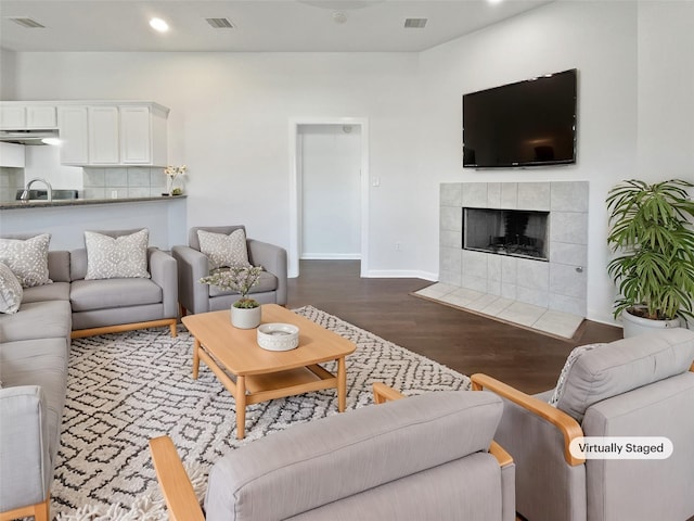 living room featuring recessed lighting, visible vents, a tiled fireplace, and wood finished floors