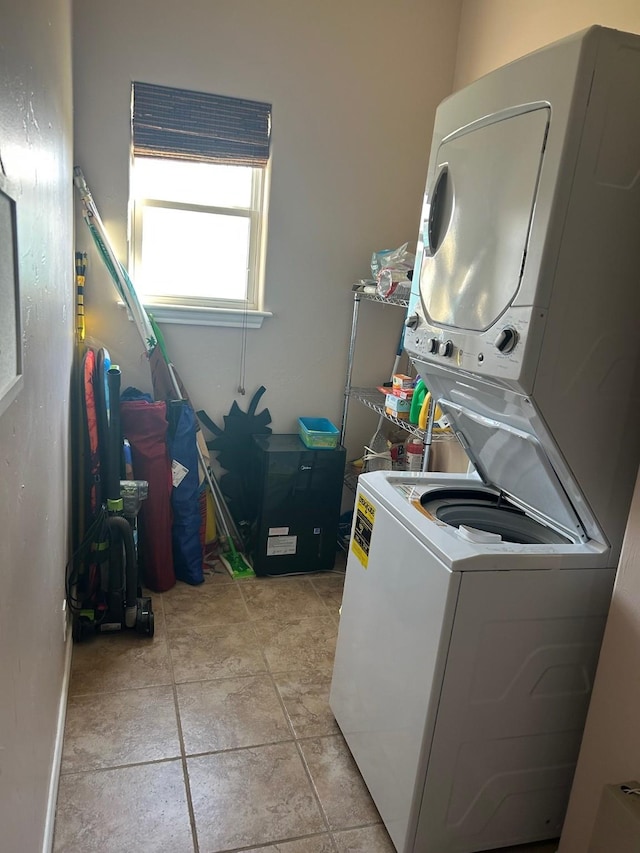 laundry area featuring laundry area, stacked washer / dryer, and light tile patterned flooring