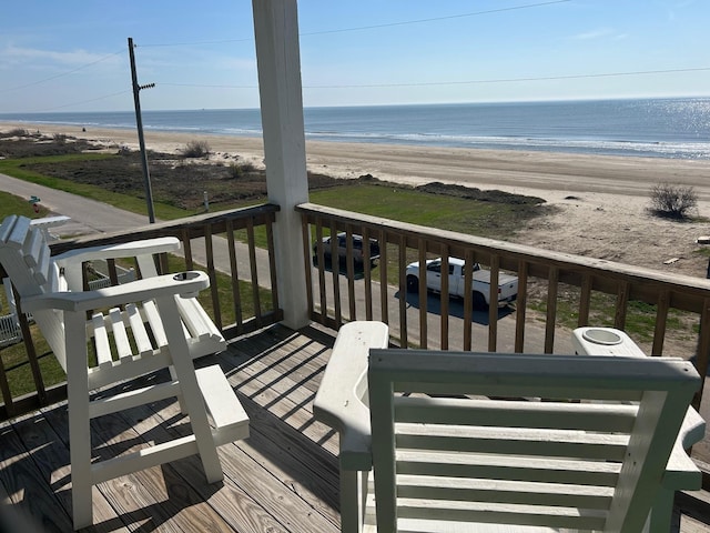 wooden terrace featuring a beach view and a water view