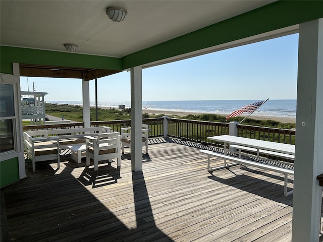 wooden deck featuring a beach view and a water view