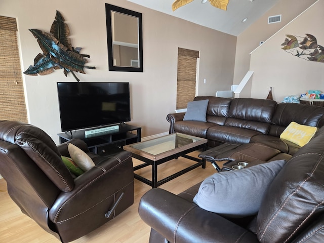 living area with visible vents, vaulted ceiling, and wood finished floors