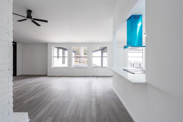 unfurnished living room featuring ceiling fan, baseboards, and wood finished floors